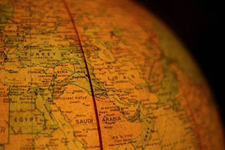A close-up photograph of a globe with the Middle East in view.