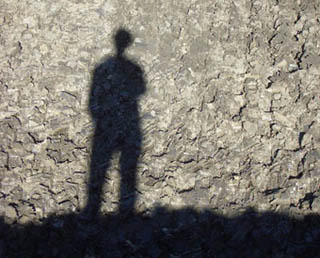 Person's shadow against a rocky wall; shadow is off-center, slightly to the left, and is full body. Person's shadow against a rocky wall; shadow is off-center, slightly to the left, and is full body.
