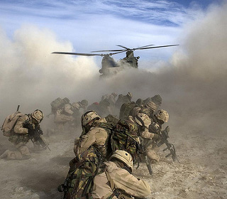 Soldiers in Afghanistan crouch in the sand as a helicopter landing causes a massive sandstorm.