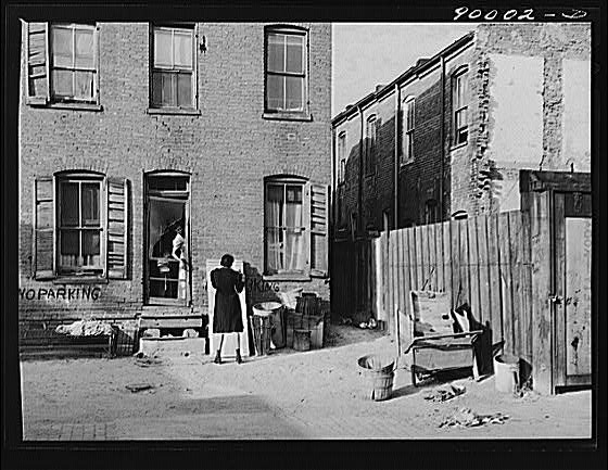 Negro slums. Alexander Court between K and L streets, N.W. Woman and her two children have lived in four small rooms eight and one half years and pay twelve fifty a month for rent. Water and privy in the yard. Rents in nearby houses have gone up but not here. Washington, D.C..