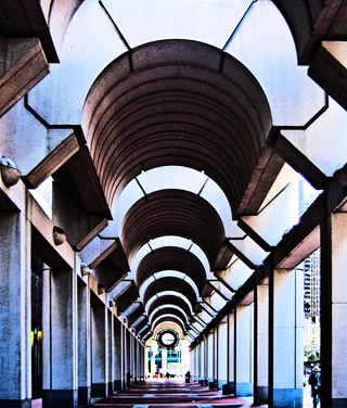 Photograph of a corridor in the Federal Reserve Bank. The semicircular arches are interspersed with open areas that allow the light in. The photograph shows lines of perspective that start near the top and meet near the bottom of the photograph.