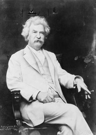 Photograph of Samuel Clemens, seated, wearing a white suit and holding a cigar.