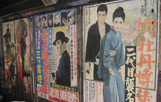 Series of three color Japanese movie posters on a wall.