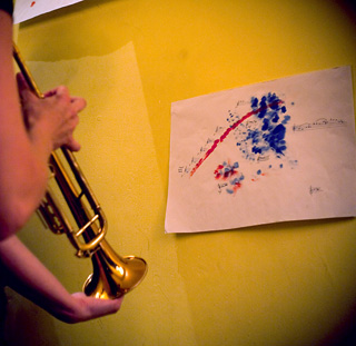 Photo of trumpet playing a graphic score, taped to the wall.